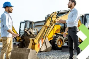Gerente comercial apresenta as opções e vantagens do aluguel de máquinas pesadas para um cliente em um pátio com uma frota de escavadeiras."