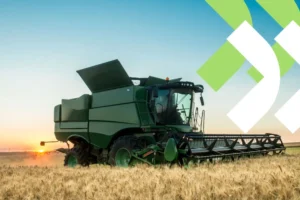 Colheitadeira amarela em plena operação, colhendo grãos em um vasto campo agrícola sob um céu azul, ilustrando o tema de custo de maquinário no agronegócio.