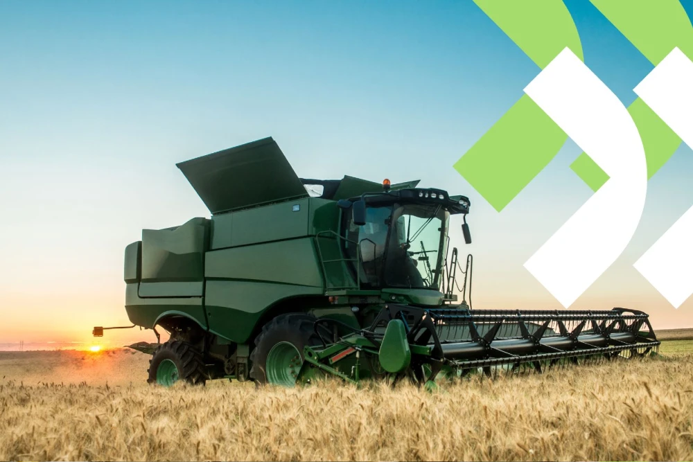 Colheitadeira amarela em plena operação, colhendo grãos em um vasto campo agrícola sob um céu azul, ilustrando o tema de custo de maquinário no agronegócio.