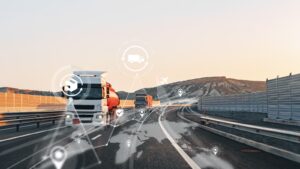 Caminhões em rodovia ao entardecer com ícones de rastreamento e pontos de localização sobrepostos, representando a gestão de ativos por telemetria