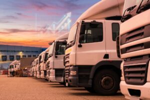 Pátio logístico ao entardecer com caminhões e implementos organizados, representando o modelo asset light aplicado à gestão de frota pesada
